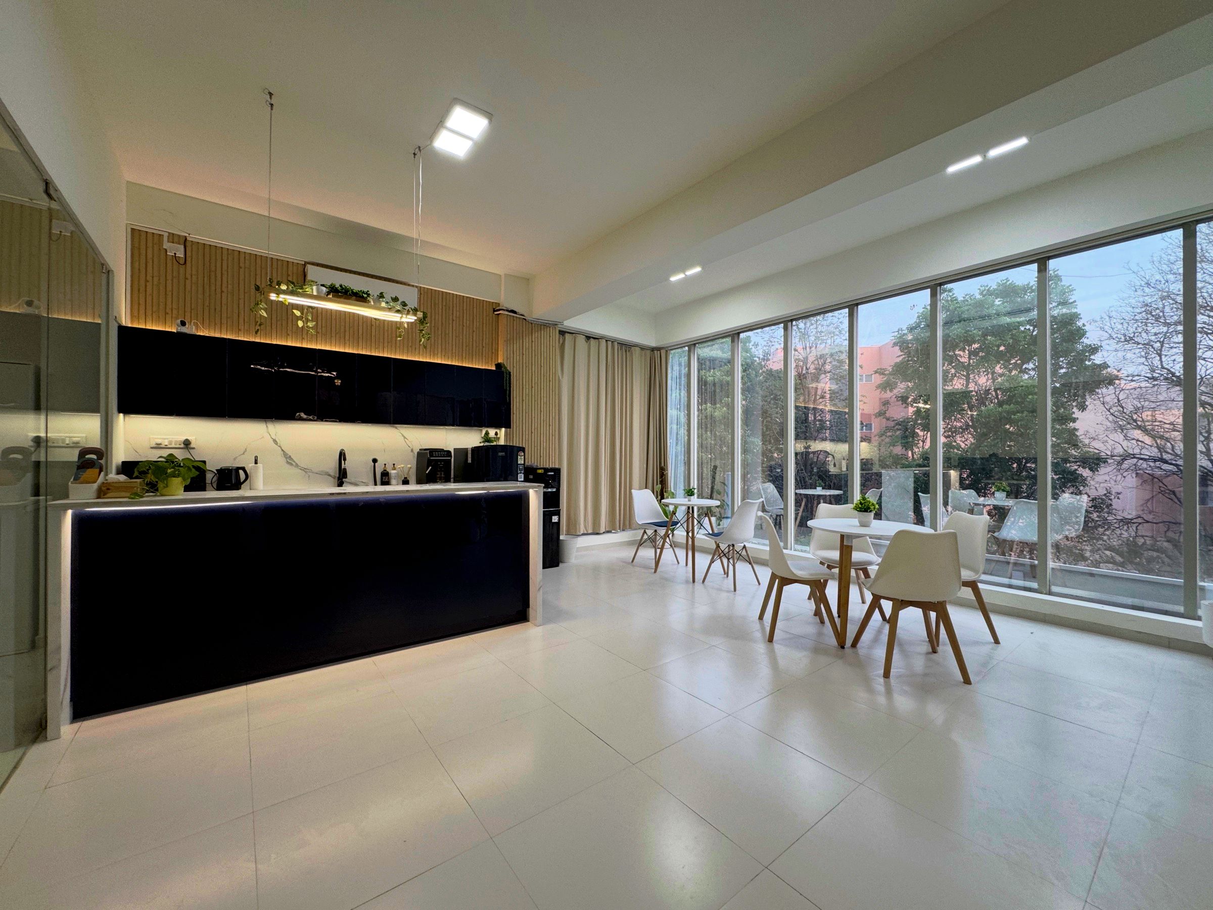 Breakout area of the Bangalore office with a coffee machine, café tables and floor-to-ceiling windows onto a balcony.