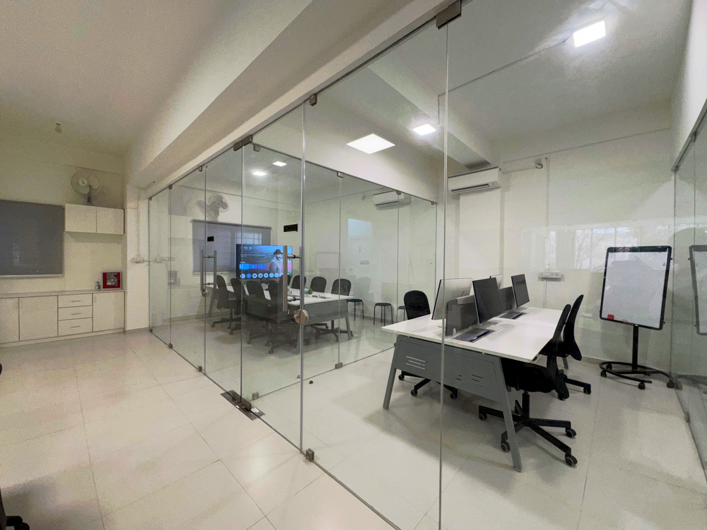Glass-walled meeting room in the Bangalore office with a large display, conference table and whiteboards.