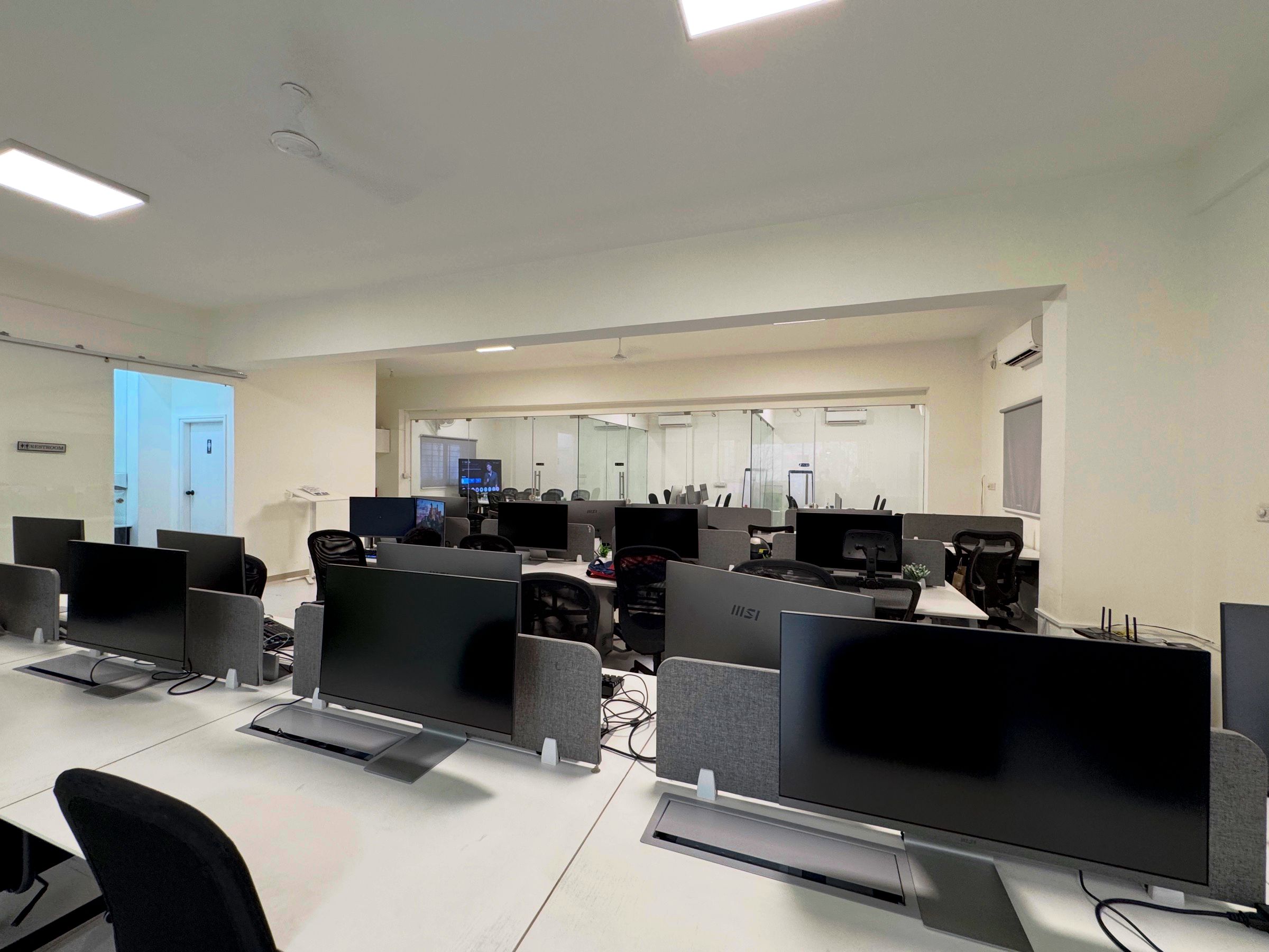 Workstations in the Bangalore office, each with a widescreen monitor, acoustic divider and in-desk cable management.